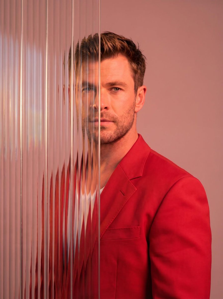 A striking editorial portrait photograph of a person wearing a red blazer, shot against a soft ligh…